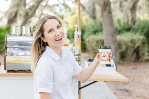 Person smiling holding a coffee cup outdoors
